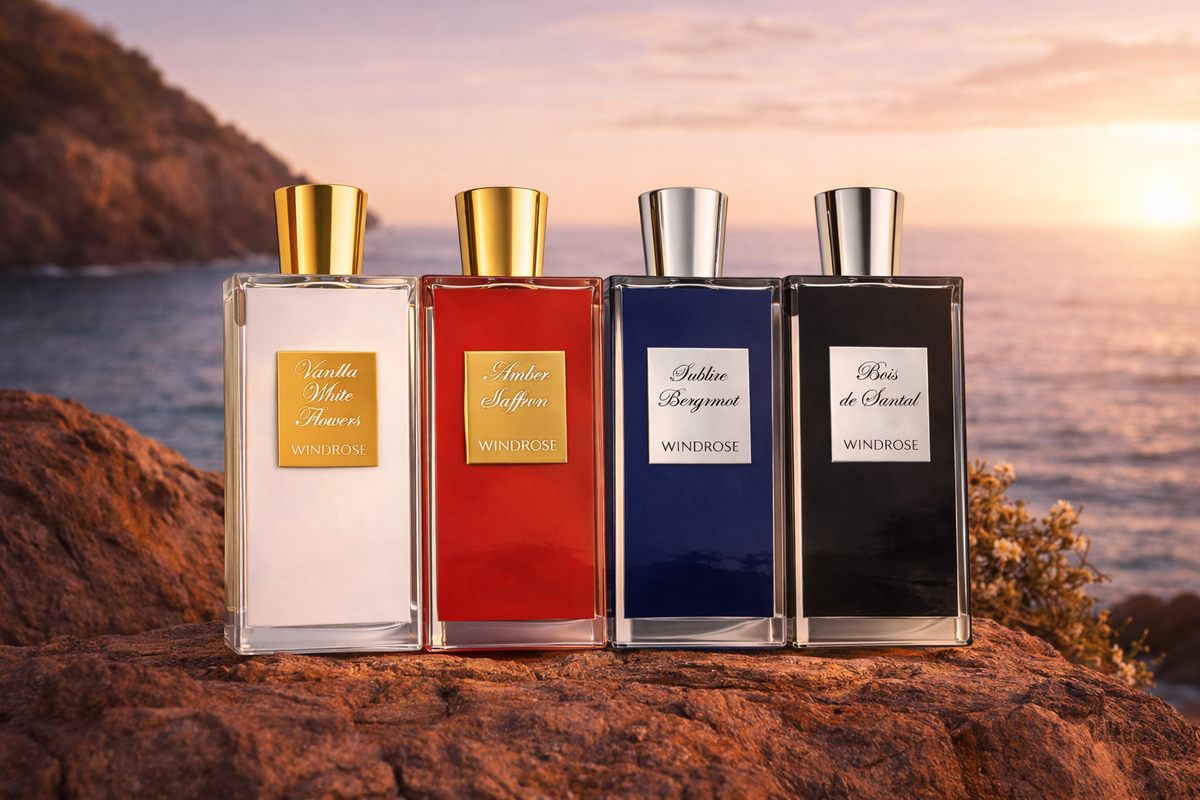 Four perfume bottles of different colors on a rocky surface with a scenic background.